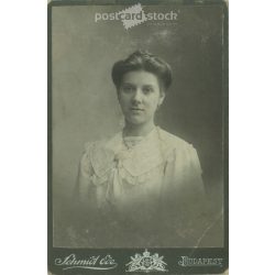  1900-as évek eleje. Fiatal nő műtermi portréfotója. Személye ismeretlen. A fotó Schmidt Ede fényképészeti műtermében készült, Budapesten. Eredeti kabinetfotó / keményhátú fotó / vizitkártya, CDV fotó. (2792350)