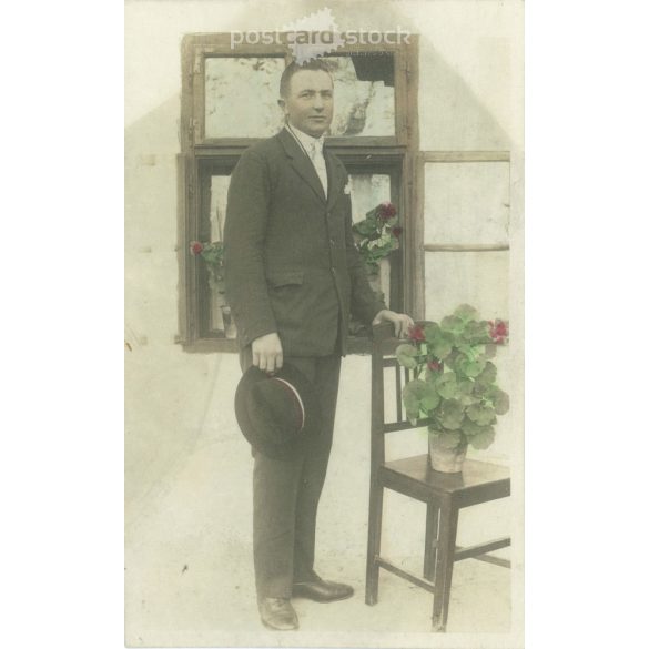 1900-as évek eleje. Fiatalember a ház előtt, muskátlikkal. Eredeti papírkép. Régi fotó. Színezett, vágott fotólap, régi képeslap. (2792655)